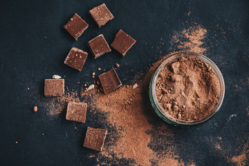 Top view of cocoa powder and chocolate pieces in black background