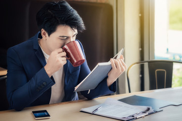Asian businessmen eating coffee while working in the morning.
