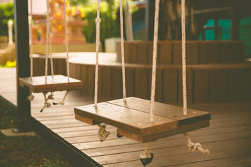 Swing woodedn seat with rope in playground, vintage toned