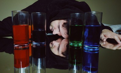Hombre joven sobre un espejo con vasos llenos de bebida 
