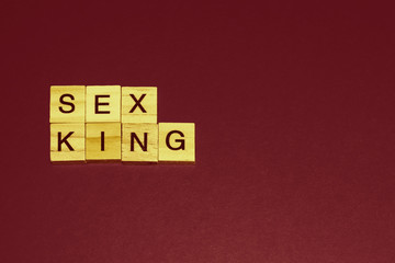 Wooden blocks on a red background spelling words Sex King. Art style