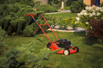 Blurred background of the home garden and lawn mower on mown grass.