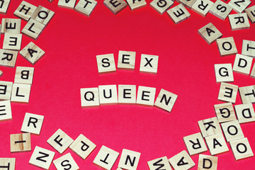 Wooden blocks on a red background spelling words Sex Queen