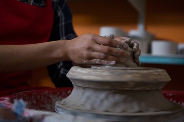 Mid section of female potter molding a clay