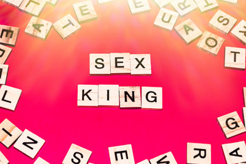 Wooden blocks on a red background spelling words Sex King