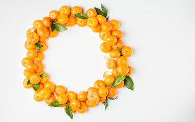 Christmas  tangerine mood!) Wreath made of  fresh small tangerines and green leaves on white wooden background. The best xmas celebration background.   Flat lay, top view, copy space. 