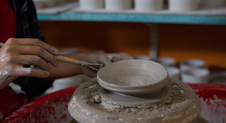 Female potter molding a bowl with hand tool