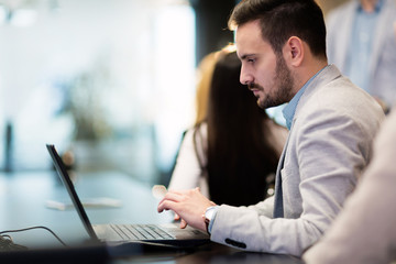 Fototapeta premium Attractive young businessman working on laptop in office