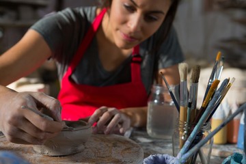 Female potter molding a bowl with hand tool
