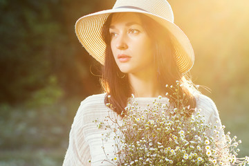 Beautiful sunny girl / woman in white dress and straw hat with bouquet of wildflowers - 185234820