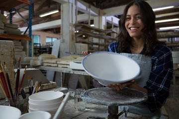 Fototapeta na wymiar Portrait of female potter painting bowl