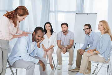 Fototapeta na wymiar psychotherapist supporting african american man during group therapy