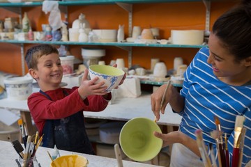 Female potter and boy painting bowl
