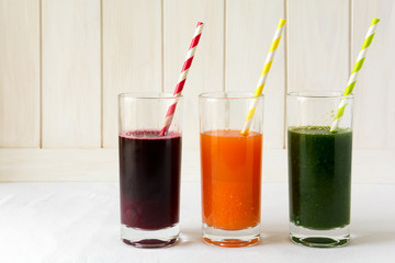 Detox drinks in glasses: fresh smoothies from vegetables: beet, carrot, spinach, cucumber and apple on white background