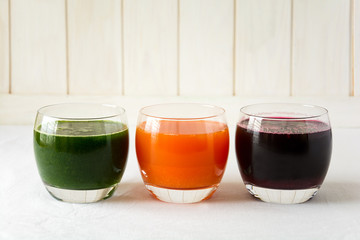 Detox drinks in glasses: fresh smoothies from vegetables: beet, carrot, spinach, cucumber and apple on white background