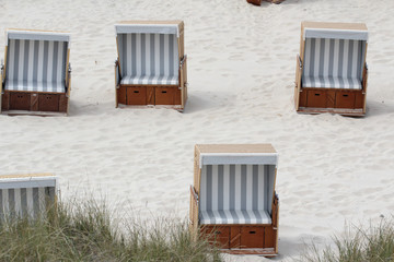 4 grau-weiße Strandkörbe am Strand bei leicht bedecktem Himmel hinter grünem Dünengras.Where: Nordsee, Sylt, Kampen.When: 11.06.2016 7:38.