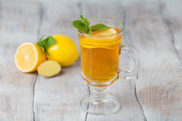 Lemon ginger tea in glass with mint and honey on a white background.  Close-up.