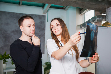 Young professional female doctor showing x-ray of human scull during patient's visit. Health medicine diagnostics concept