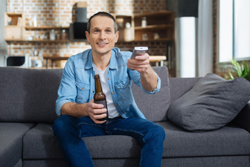 Free time. Attractive man smiling and using console while choosing program