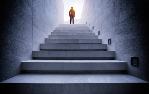 Businessman standing on top of concrete stairs with sun light