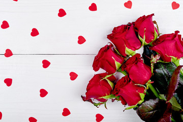 Top view of bouquet red roses and paper hearts on white wooden background, copy space. Greeting card mockup for Saint Valentines Day, Womans Day (March 8), Mothers Day. Love, wedding concept, flat lay