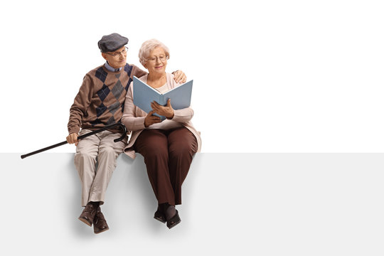 Elderly couple sitting on a panel and reading a book