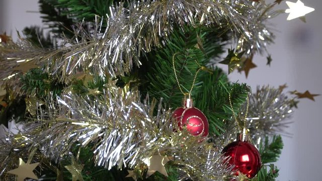 A woman's hands decorating Christmas tree with a red ball at home