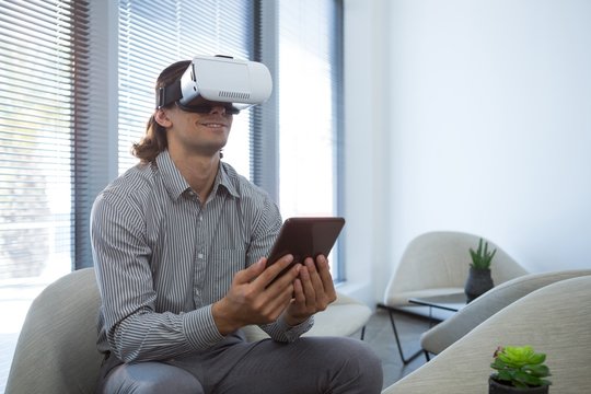 Male executive using digital tablet and virtual reality headset