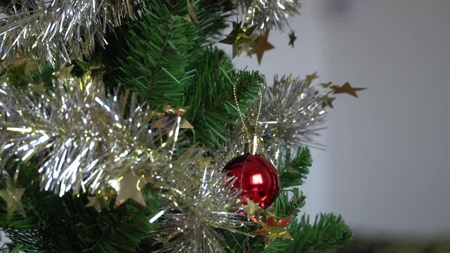 A woman's hands decorating Christmas tree with a red ball at home