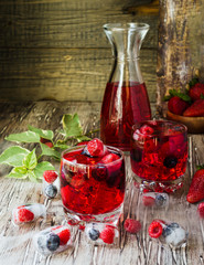 Summer berry lemonade with frozen berries on a wooden rustic table, selective focus