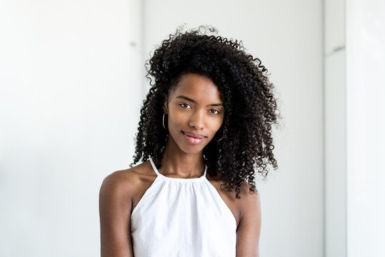 Portrait of a beautiful young black woman curly hair smiling looking into camera .
