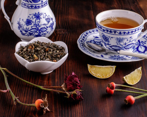 A porcelain cup with black tea. Dried citrus fruits. On a dark wooden background.