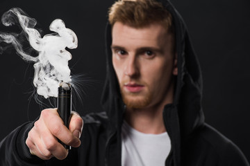 Young bearded man activating electronic cigarette