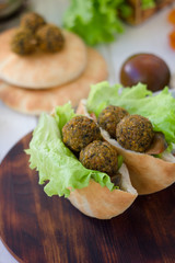 Wooden board with falafel in pita inside.