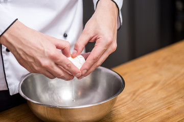 Fototapeta na wymiar cropped image of chef putting egg into bowl
