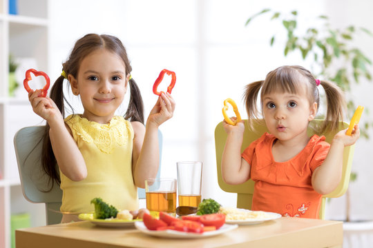 happy children eating healthy food in kindergarten or at home