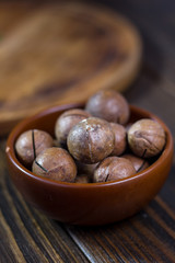 Macadamia nuts in a brown ceramic bowl.