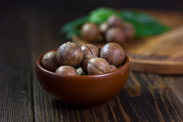 Brown ceramic bowl with macadamia nuts inside.