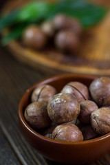 Brown ceramic bowl with macadamia nuts inside.