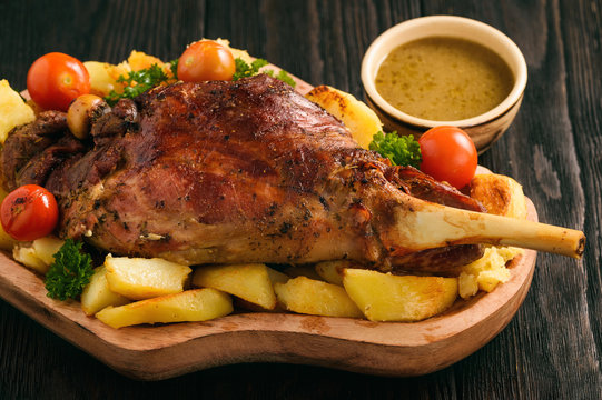Slow baked lamb leg with potatoes and sauce.