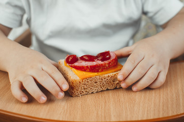 child hands holding a sandwich, bread with sausage