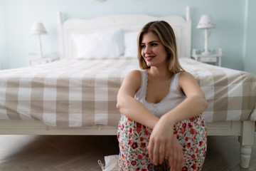 Young happy beautiful woman sitting in bedroom
