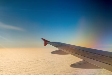 Fototapeta na wymiar Wing of airplane in with sunrise and blue sky.