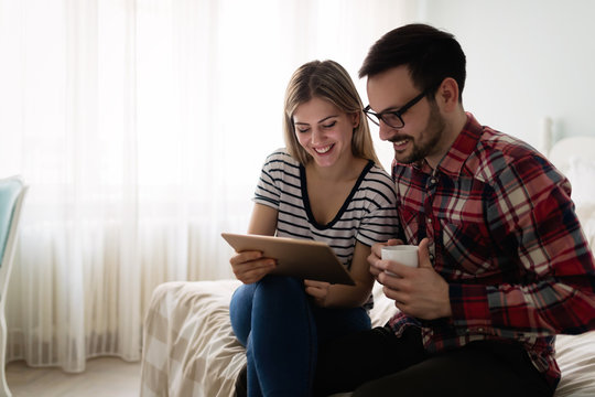 Young attractive couple using tablet in bedroom