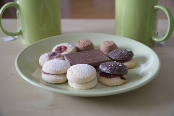 Cookies on a green plate with green cups of tea                        