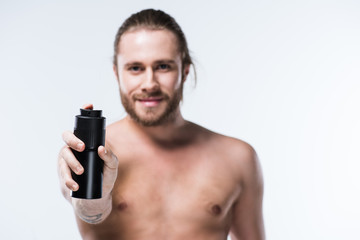 Fototapeta na wymiar Cheerful young man holding deodorant spray in outstretched hand