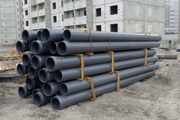 Close up of rubber pipes on pile and other construction material and equipment at building site