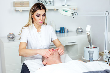 Fototapeta premium Cosmetologist is doing procedure of face massage for young boy / man. Model, close-up. Cosmetological clinic. Healthcare