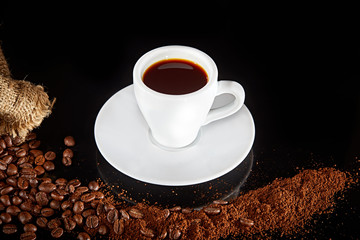 Cup of espresso ground  coffee beans on black background