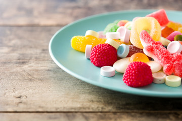 Colorful childs sweets and treats in plate on wooden table